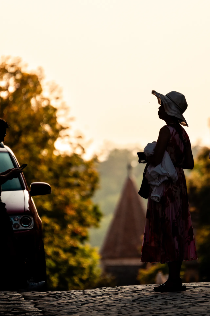 Frau im Sommerkleid, ein Hut als Schattenriss gegen den Abendhimmel